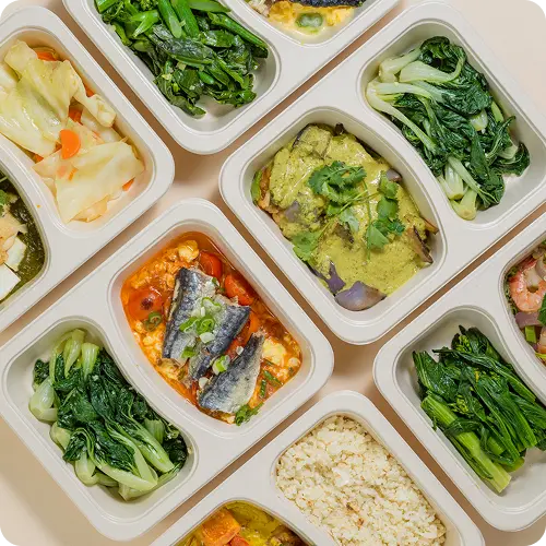 Prepared meals in individual compartments on a beige background