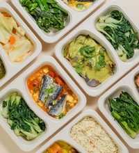Prepared meals in individual compartments on a beige background